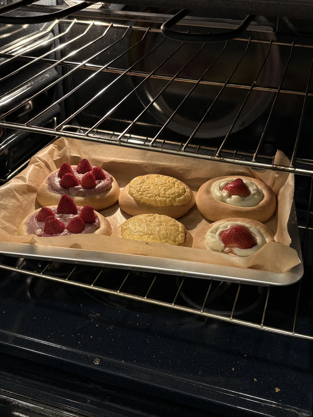 Strawberry and custard buns on a tray in the oven.