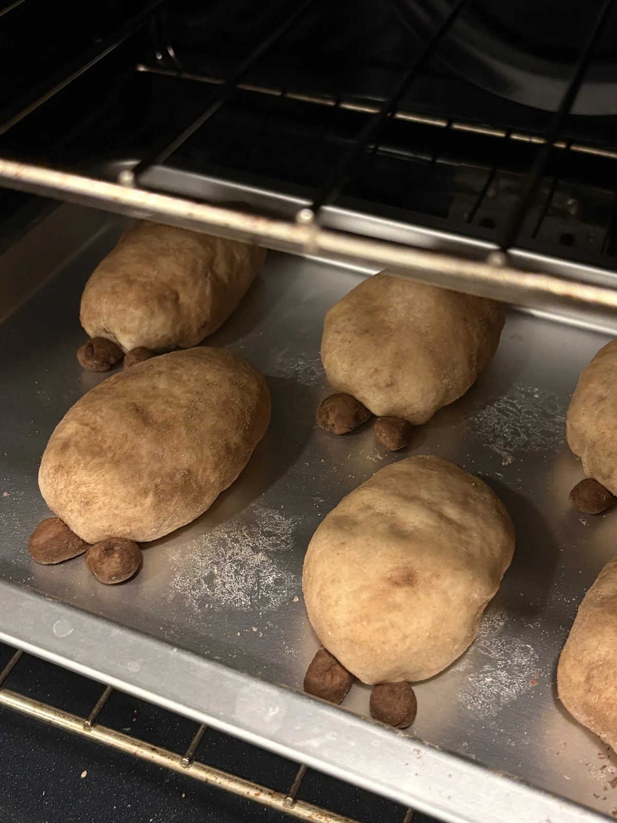 Turtle-shaped buns baking on a metal tray.
