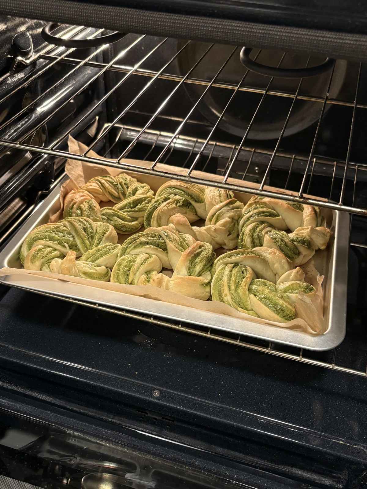Twisted green pesto buns baking in the oven.